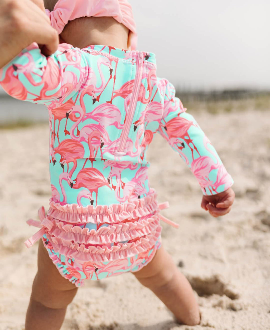 RuffleButts Baby Girls UPF 50+ Sun Protection Tropical Print Long Sleeve One Piece Rash Guard Swimsuit with Zipper - Fab Flamingo, 3-6m